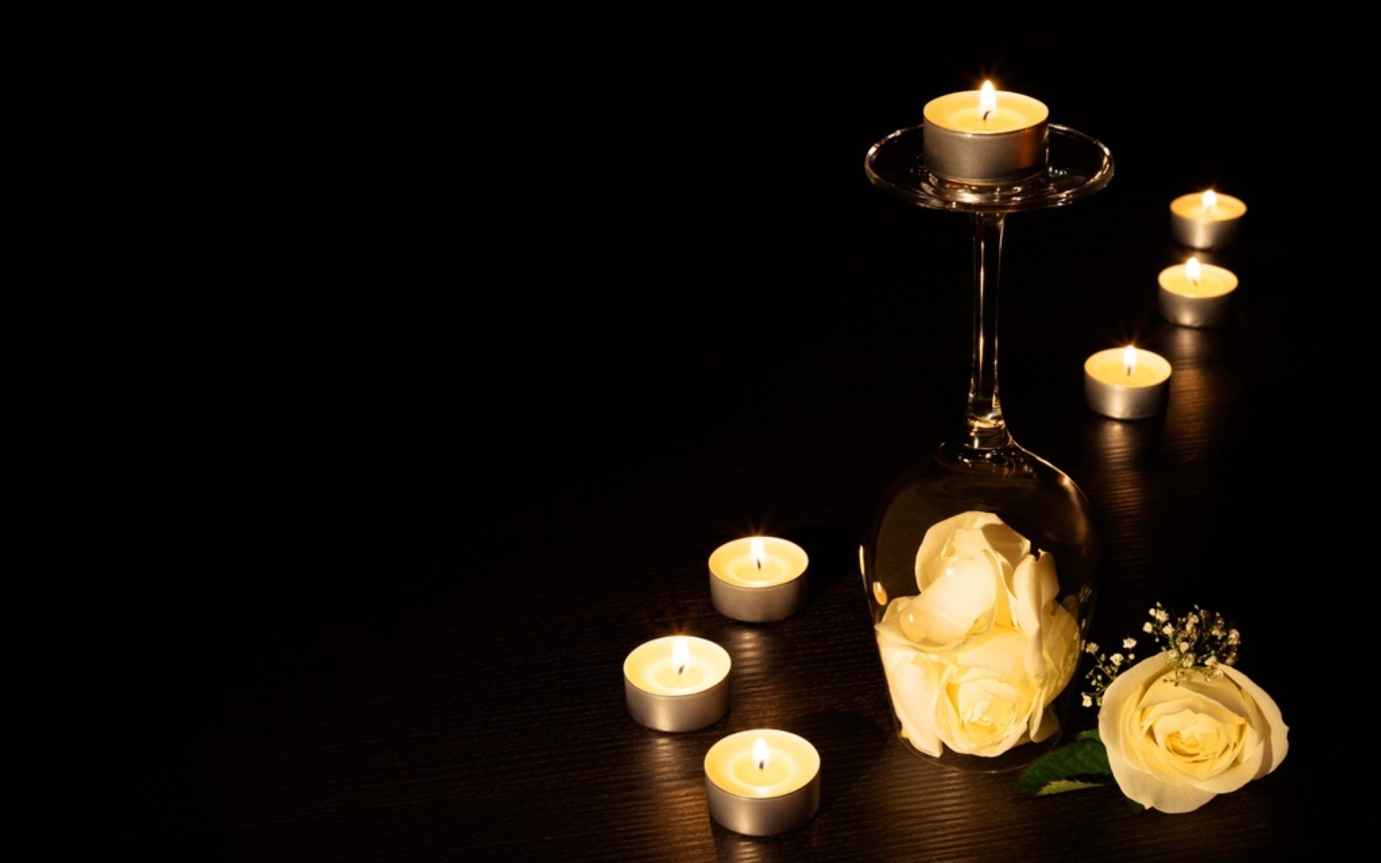 Candles and roses arranged together in warm, low light