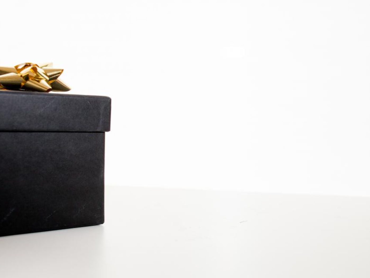 A black gift box finished with a gold bow