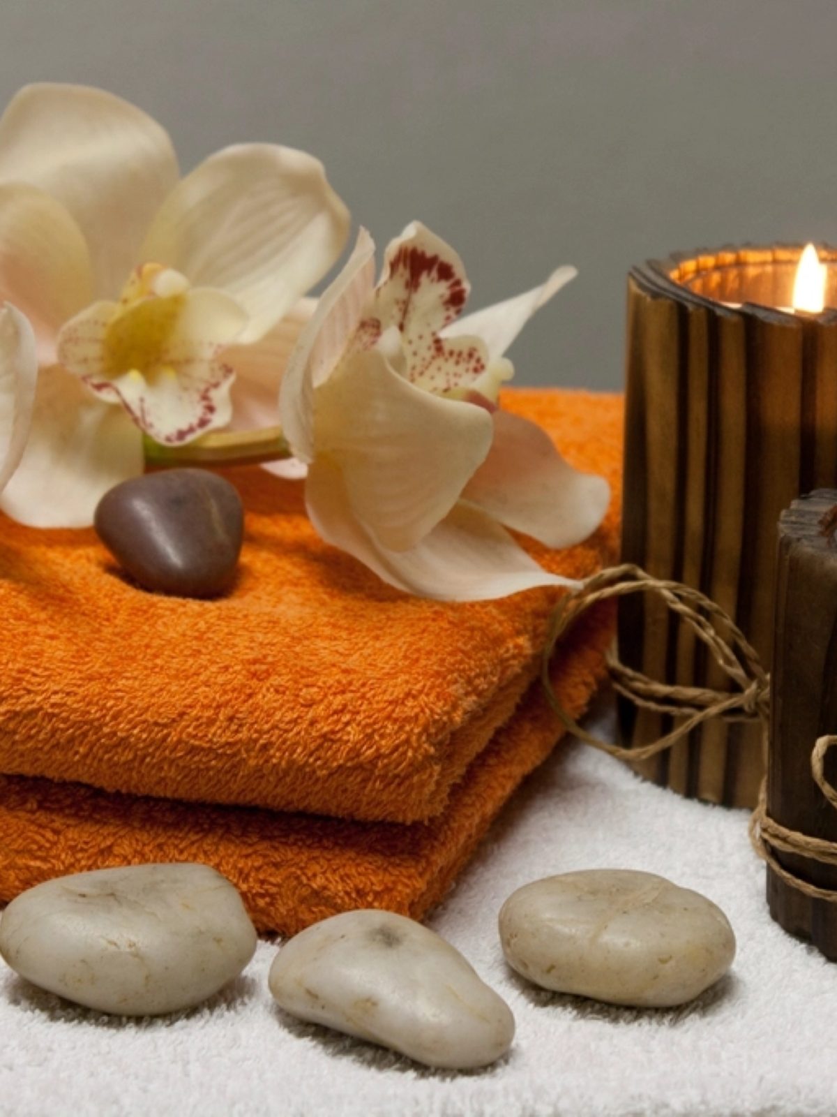 Candles, orchids and smooth stones arranged on a tray