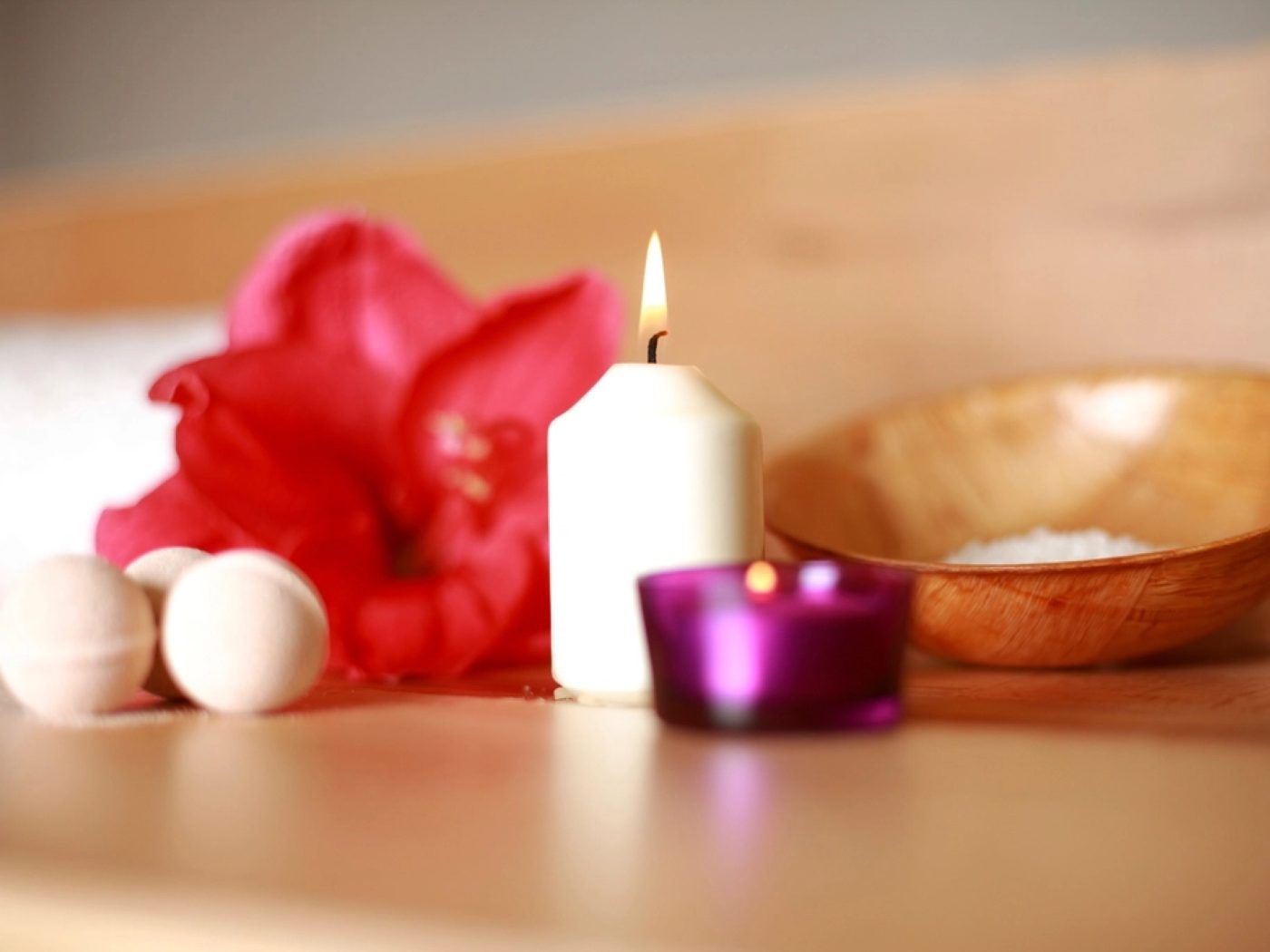 Candles arranged with a red bloom and a wooden bowl
