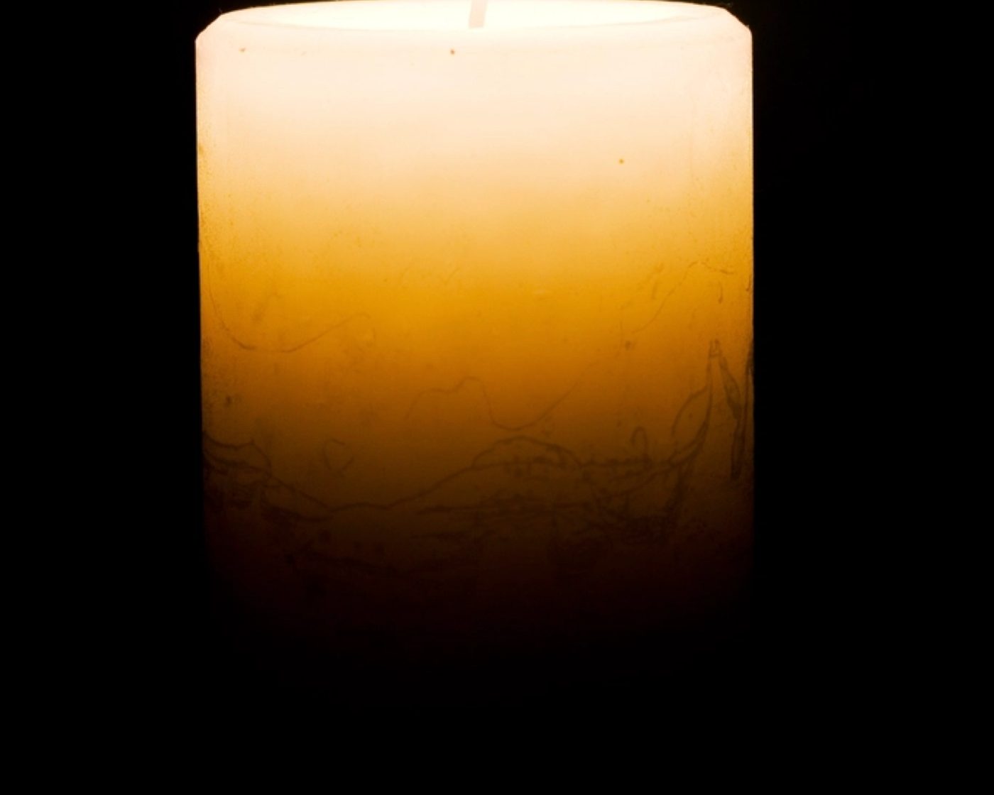 A single candle flame glowing in the dark