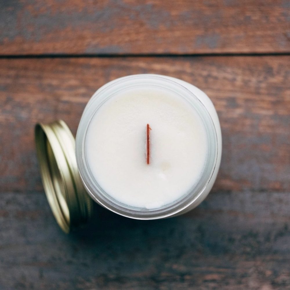 A white candle in a glass vessel with a gold lid