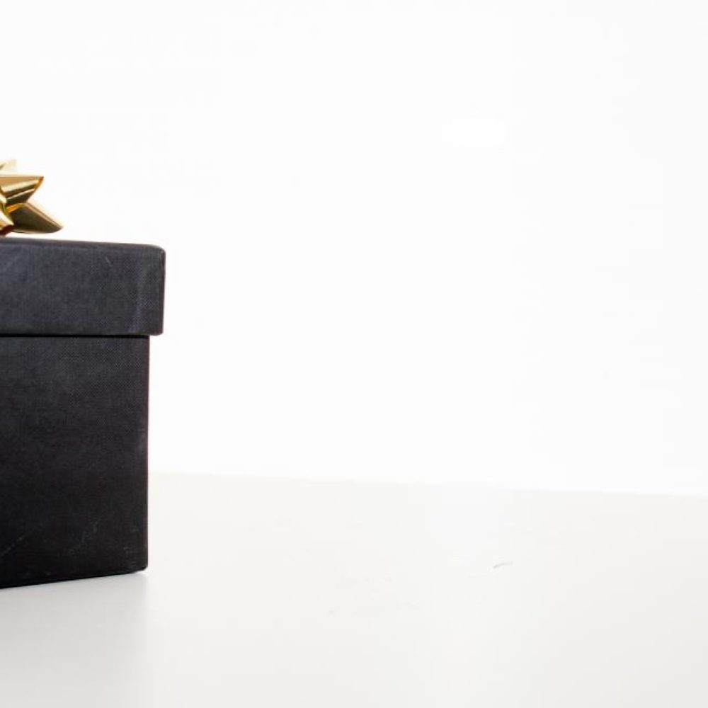 A black gift box finished with a gold bow