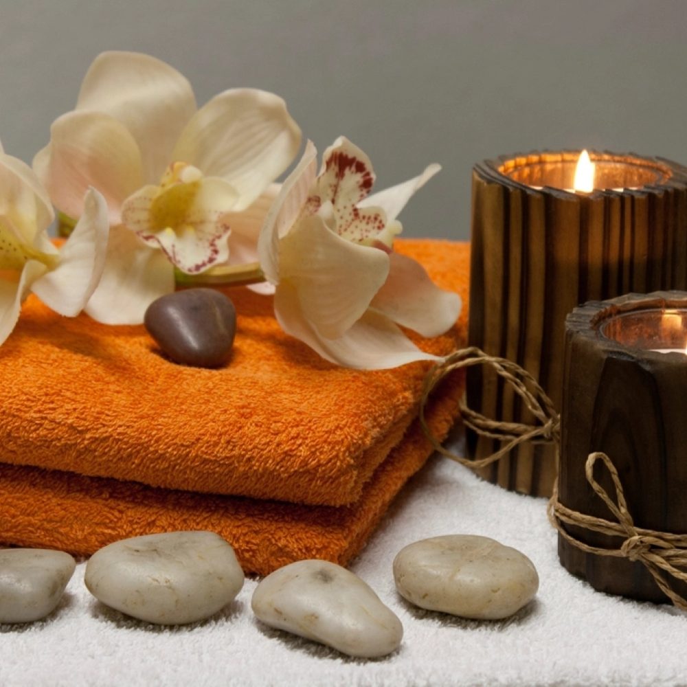 Candles, orchids and smooth stones arranged on a tray