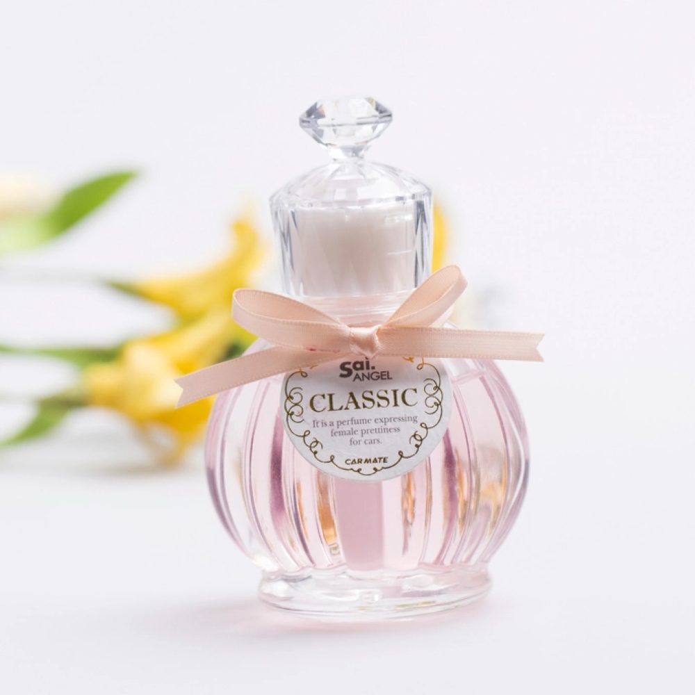 A fragrance bottle tied with a ribbon beside flowers