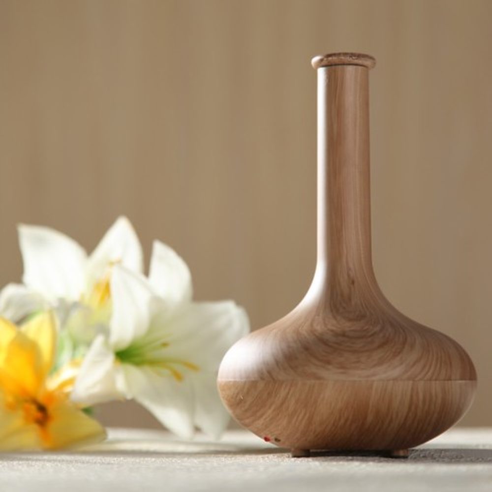 A wooden diffuser beside a white lily