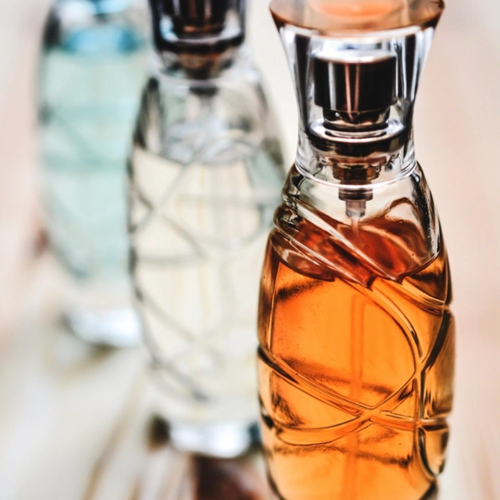 Three fragrance bottles arranged on a wooden surface